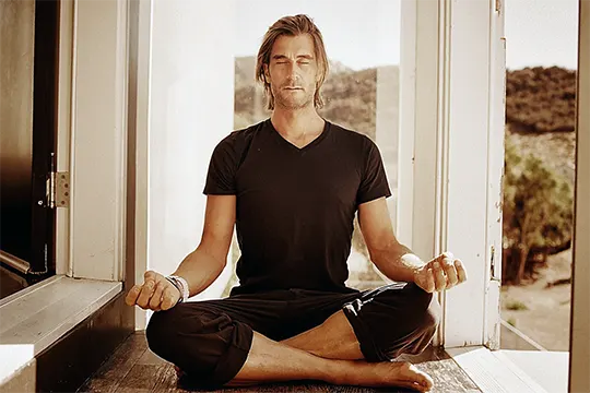 rich roll sentado de pernas cruzadas em frente a uma janela